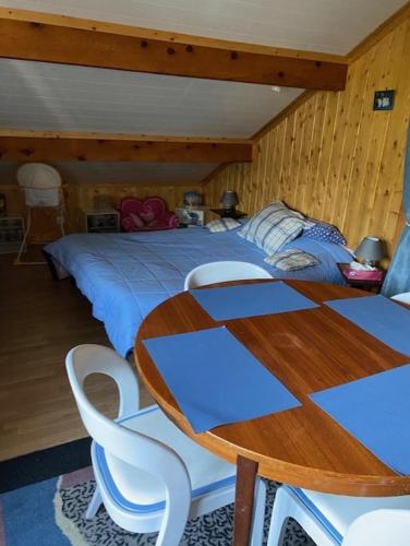 - une chambre avec un lit, une table en bois et des chaises dans l'établissement studio des perce neige, à Barcelonnette