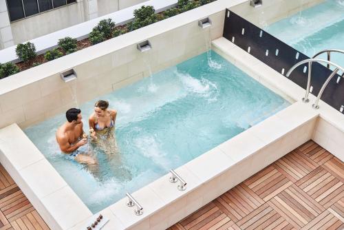 two men in a jacuzzi swimming pool at Thompson Dallas, by Hyatt in Dallas