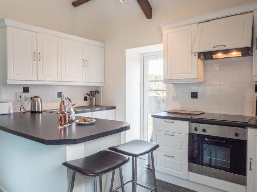 a kitchen with white cabinets and black counter tops at The Old Forge Llandeilo in Carmel