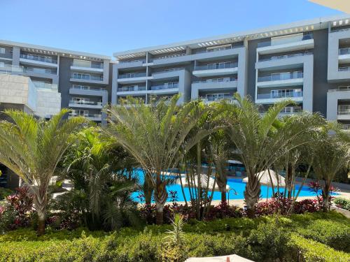 Hotel exceptional luxury apartments next to Cairo airport at ocean blue compound Heliopolis في القاهرة: منتجع فيه نخل امام مبنى