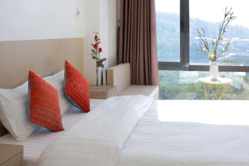 a bedroom with a bed with orange and white pillows at Cong Fu Hotel in Bắc Hà