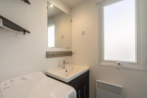 une salle de bain blanche avec un lavabo et un miroir dans l'établissement Siblu Bonne Anse Mobilhome 510, aux Mathes
