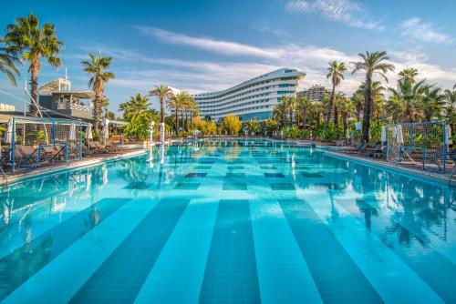 a large swimming pool with palm trees and a hotel at Concorde De Luxe Resort Lara Antalya- Prive Ultra All Inclusive in Lara