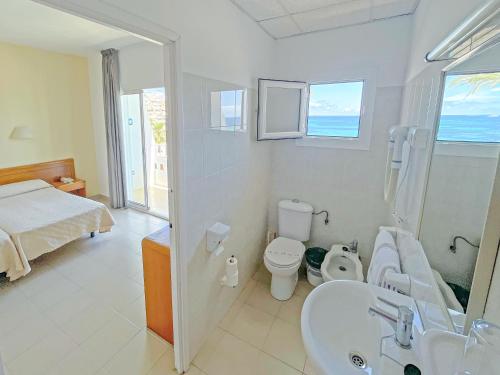 a bathroom with a bed and a sink and a toilet at Hotel Figueretes in Ibiza Town