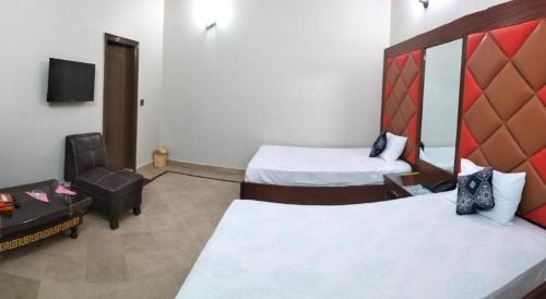 a hotel room with two beds and a chair at GULSHAN PALACE Near Agha Khan Hospital Expo Center Airport in Karachi