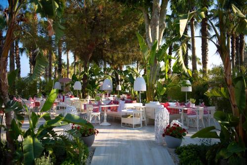a restaurant with white tables and chairs and trees at Miramare Beach Hotel - Ultra All Inclusive in Side