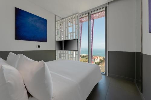 a bedroom with a white bed and large windows at Wink Hotel Tuy Hoa Beach - 24hrs Stay & Rooftop Pool Bar in Tuy Hoa