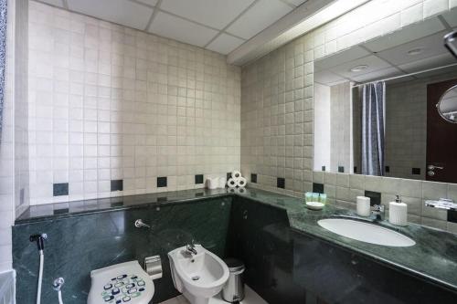 a bathroom with a sink and a toilet and a mirror at HiGuests - Incredible City Views in Deira 5-min to Airport in Dubai