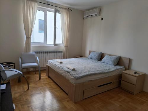 een slaapkamer met een bed met een stoel en een raam bij Apartman Quality in Voždivac