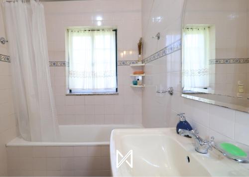 a bathroom with a sink and a tub and a mirror at MyStay - Casa da Carvalha in Arcos de Valdevez