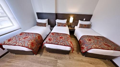 a room with three beds in a room at AZ Hotel in Bogotá