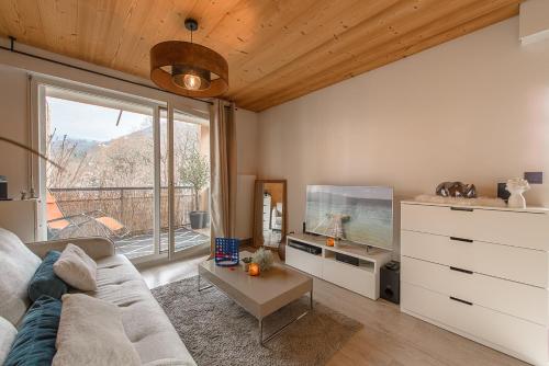 a living room with a couch and a tv at Les Terrasses Montfleury, aux portes d'Annecy- Une exclusivité LLA Selections by Location lac Annecy in Annecy