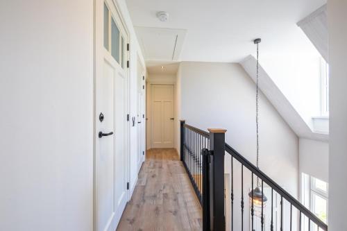 a hallway of a house with a wooden floor and a staircase at Familievilla Nieuw Zeeland in Oosterend