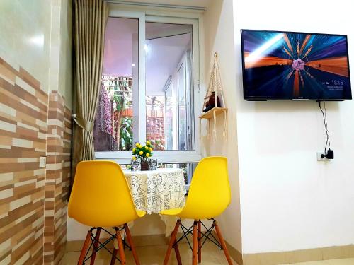 a table and two yellow chairs in a room with a window at Moon Homestay Huế in Thôn Dương Xuân Hạ