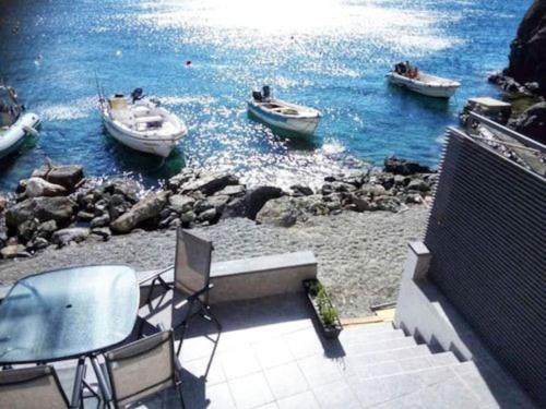 two boats in the water with a table and chairs at Sunrise Luxury Seaside Apartment in Paránimfoi