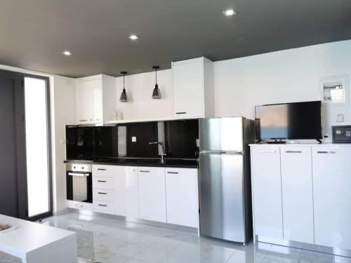 a kitchen with white cabinets and a stainless steel refrigerator at Sunrise Luxury Seaside Apartment in Paránimfoi