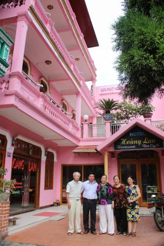 een groep mensen die voor een roze gebouw staan bij Hoang Lan Hostel in Sa Pa
