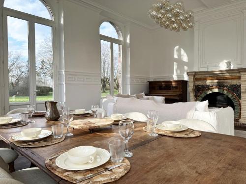 un comedor con una mesa con platos y vasos en L'Orangerie du Château - Outdoor swimming pool, en Blandainville