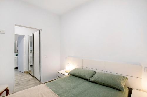 ein weißes Schlafzimmer mit einem grünen Bett und einem Spiegel in der Unterkunft The Greey's House A in Telde