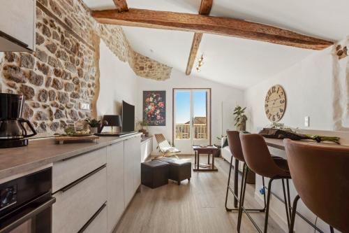 une cuisine et une salle à manger avec un mur en pierre dans l'établissement Appartement de ville Fréjus, à Fréjus