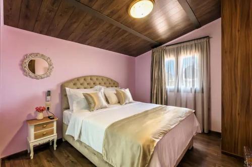 Villa Kampos في كوكيني خانيون: غرفة نوم وردية مع سرير كبير ونافذة