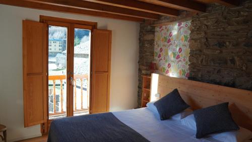 a bedroom with a bed and a large window at Cal Batlle Casa Rural in La Cortinada