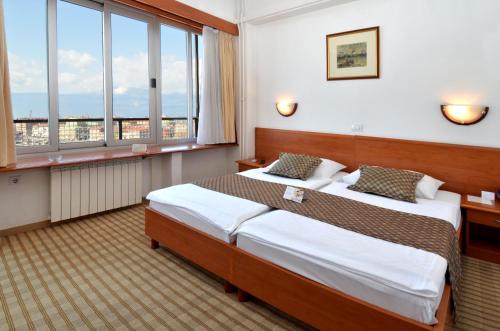 a hotel room with two beds and windows at Hotel Neboder in Rijeka