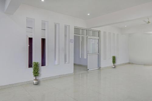 uma sala vazia com paredes brancas e vasos de plantas em OYO Flagship New Bhandan Lawn em Lucknow