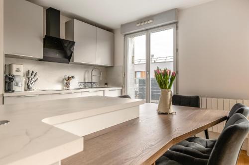 une cuisine avec des armoires blanches et une table en bois dans l'établissement Charming Terrace Apt Near Paris - Olympics, aux Lilas