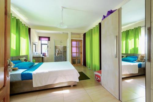 sypialnia z 2 łóżkami i zielonymi ścianami w obiekcie West Coast Villas w mieście Tamarin