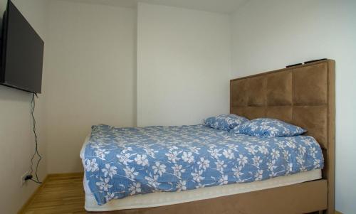 um quarto com uma cama com lençóis azuis e uma televisão em Premium stan Novi Beograd em Novi Beograd