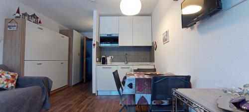 uma cozinha com armários brancos e uma mesa num quarto em Ski apartment Sellette San Sicario Alto em San Sicario