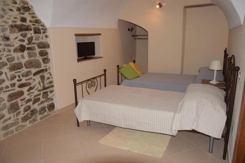 - 2 lits dans une chambre avec un mur en pierre dans l'établissement Corte Doria Dolceacqua Agriturismo, à Dolceacqua