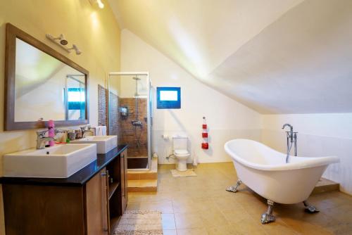 a bathroom with two sinks and a tub and a toilet at West Coast Villas in Tamarin