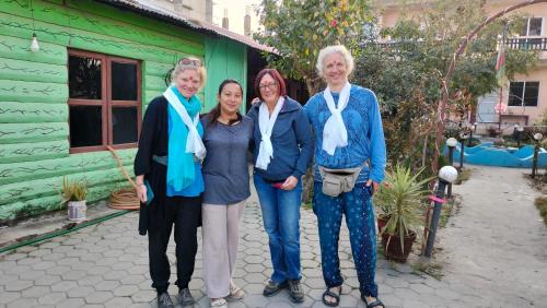 un grupo de tres mujeres frente a una casa verde en Hotel Garden of Dreams en Sauraha