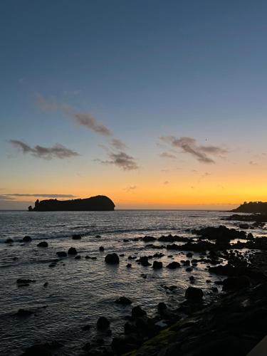 a sunset over the ocean with rocks in the water at Esplanada do Ilhéu in Vila Franca do Campo