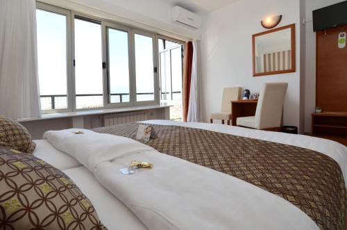 a bedroom with two beds with pillows and a window at Hotel Neboder in Rijeka