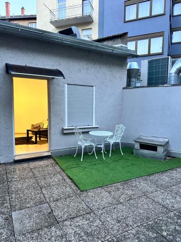 a patio with two chairs and a table on grass at Mini Haus am MA-HBF mit Parkplatz in Mannheim