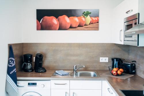 a kitchen with a sink and a picture of pumpkins at Heimathafen Schlei in Olpenitz