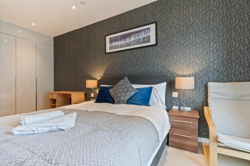 ein Schlafzimmer mit einem großen Bett mit blauen Kissen in der Unterkunft Elegant 2BR flat on 20th floor near many attractions in London