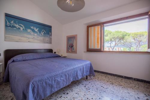a bedroom with a bed with a blue comforter and a window at La Torretta - HelloElba in Marina di Campo