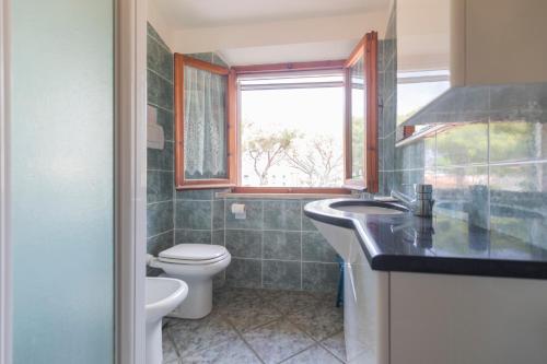 łazienka z toaletą, umywalką i oknem w obiekcie La Torretta - HelloElba w mieście Marina di Campo