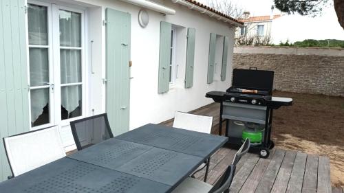 a patio with a grill and a table and chairs at SOLÈSE Maison avec spa à 500m de la plage in Le Bois-Plage-en-Ré