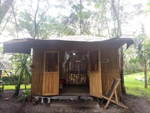 a small hut with an open door in a forest at Red Rocks Rwanda - Bamboo Cottage in Nyakinama