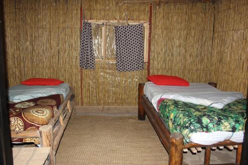 a room with two beds and a window at Red Rocks Rwanda - Bamboo Cottage in Nyakinama