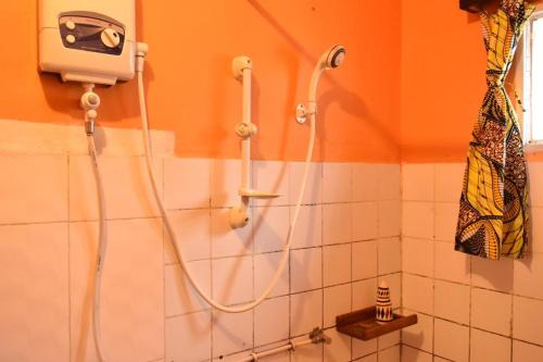 a shower in a bathroom with a hose on the wall at Room in BB - Amahoro Guest House - Double Room with Private Shower Room in Ruhengeri