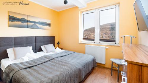 um quarto com uma cama, uma secretária e 2 janelas em Wonder Home - Apartament Górska Panorama z widokiem na uzdrowisko i Góry Izerskie em Świeradów-Zdrój