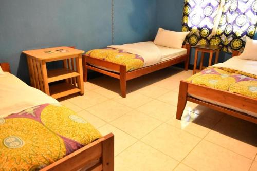 a room with three beds and a table and two chairs at Room in BB - Amahoro Guest House - Triple Room with Shared Bathroom in Ruhengeri