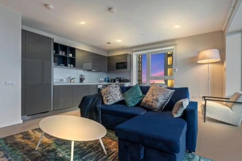 a living room with a blue couch and a table at Elegant 2BR flat on 20th floor near many attractions in London