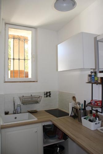 une cuisine blanche avec un évier et une fenêtre dans l'établissement Agréable appartement P2 Centre ville au calme., à Nîmes